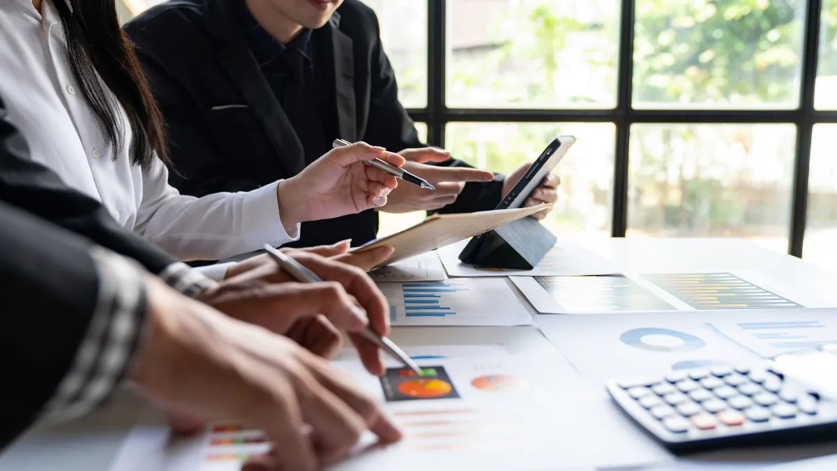 Colleagues reviewing financial charts beside a calculator and tablet