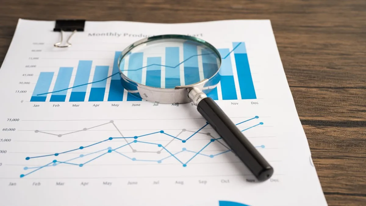 A magnifying glass resting on printed financial charts
